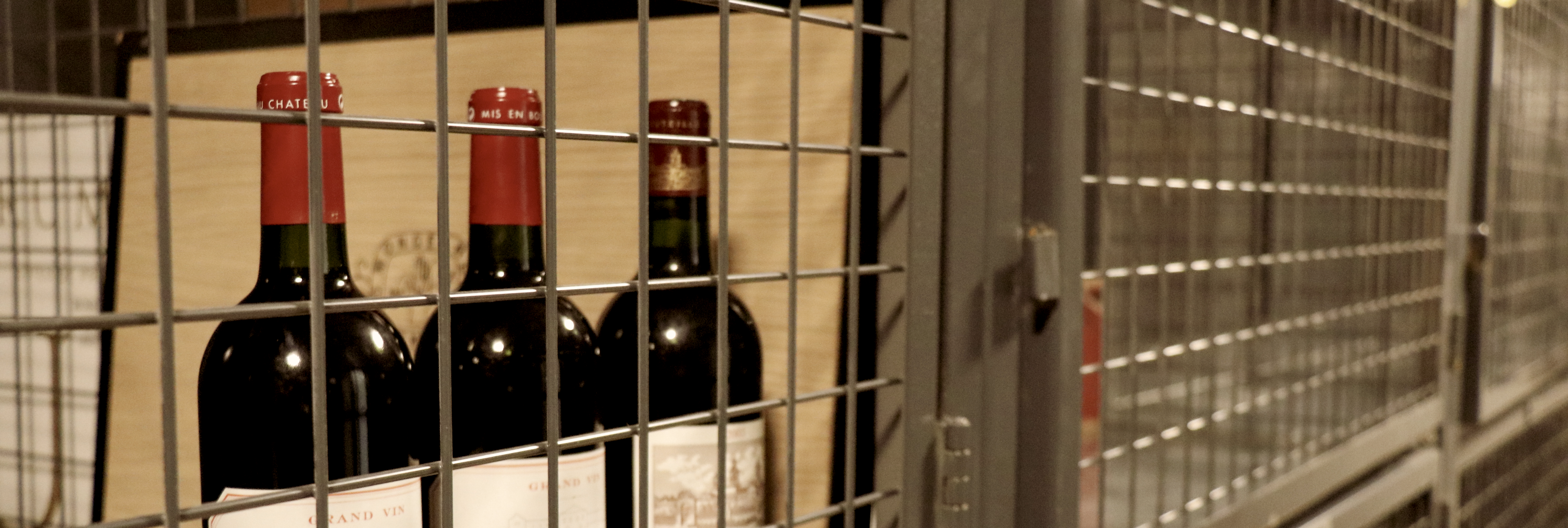 Three wine bottles securely stored in a temperature-controlled storage unit at Cáve a Vin at StorSpaces.